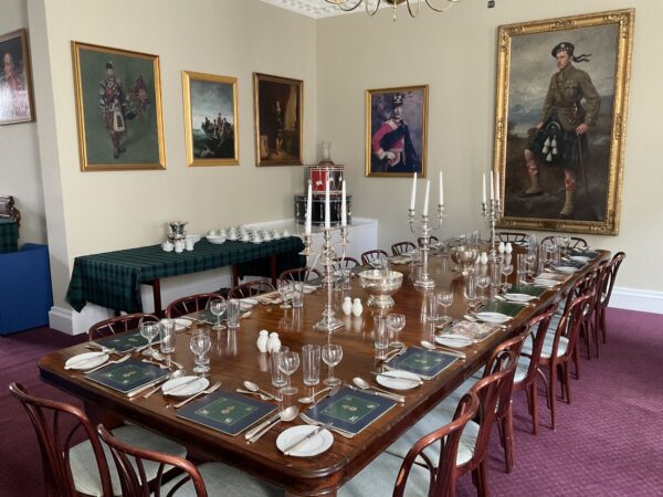 The dining table in the Colonel's room, fully set for a meal with place settings and candles