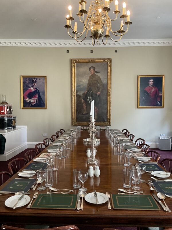 The dining table in the Colonel's room, fully set for a meal with place settings and candles